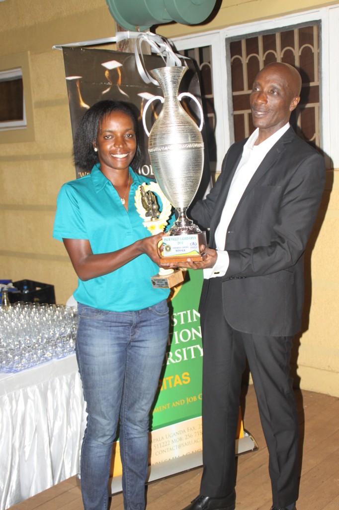 Overall winner of the Inaugural Palm Valley Ladies Open Golf Tournament Namakula Flavia receiving her trophy from Police Boss Gen. Kale Kayihura.