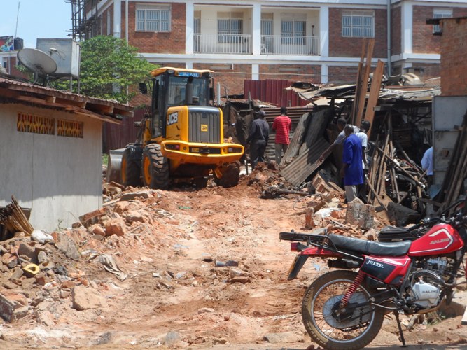 A grader leveling the ground after demolishing several kiosks in Kitoro.