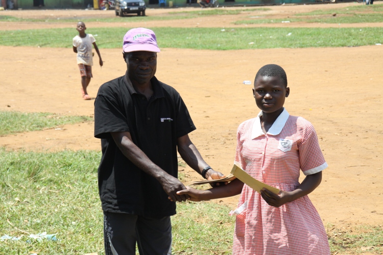 Bugonga Primary School's Aneno Monica receives Shs 10,000 cash prize from Coach Nsubuga Joseph. She finished second in the Girl's 5Km race.