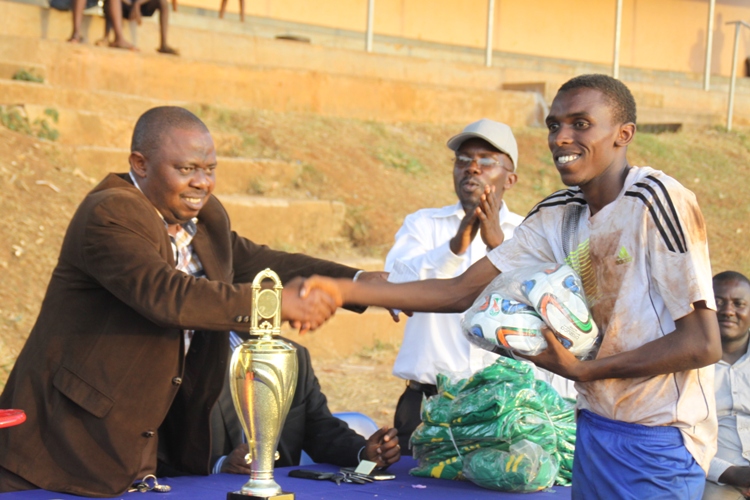 Merry Land Captain Kamurasi Patrick receives two balls from Fufa Vice President Justus Mugisha.