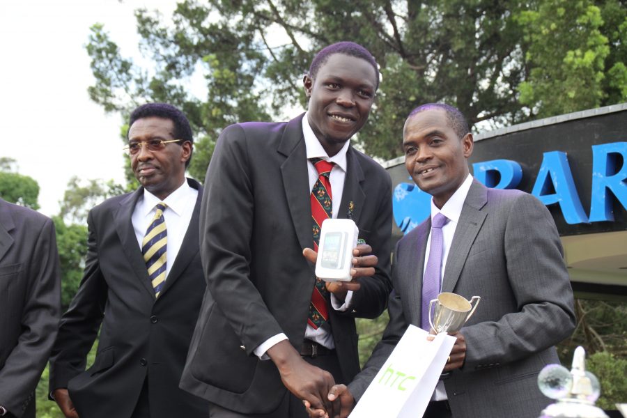 Dr. Sebaale handovers an HTC Mobile Handset to Martin Ochaya after winning the longest drive competition.