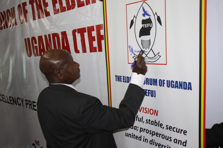 President Museveni signs on the banner to launch the forum.