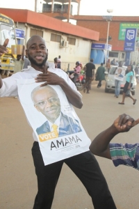 A down town trader smiling with Mbabazi poster.