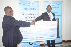 Bamwesigye (L) hands over the Shs 10.6m cheque to Kisuze Stephen.