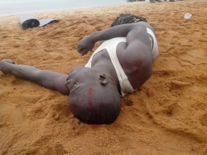 Body with blood stains lying at beach shores.