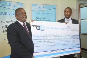 CAA Director For Human Resource and Administration Fred Bamwesigye hands over a Shs10.6m cheque to Kisuze.