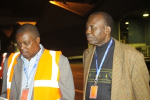 EC Head of Election Management Joshua Wamala and Commissioner Tom Buruku at Entebbe Airport.