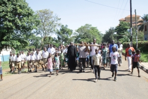Father Sebayiga (in black robe) led a procession on Good Friday. He urged Christians to embrace the cross of Jesus Christ.