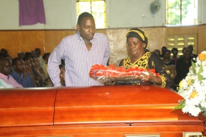 Widow Podi Kassami lays a wreath on her departed husband's casket.
