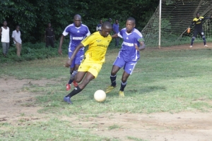 Onesmus Andama (yellow) dribbles past Wandegeya players.