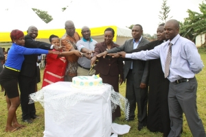 Hon. Tumusiime and the TASO executive members join hands in cutting a cake during the 19th General Assembly meeting.