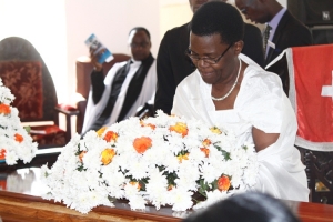 Joy Kahangirwe lays a wreath on her late husband's casket.