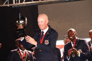 Team Kenya Coach John Van Leaf land smiles with trophy.