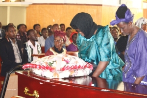Grace Otim (with veil) lays wreath on her late husband's casket.