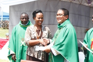 Outgoing Chairperson Specioza Kaita receives her certificate of Appreciation from Rev. Fr. Raymond Kalanzi.