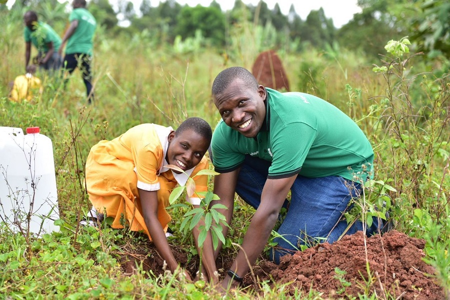 Moses Rutahigwa the Head Consumer, Private and Business Banking at Standard Chartered Bank plants a tree with one of the children
