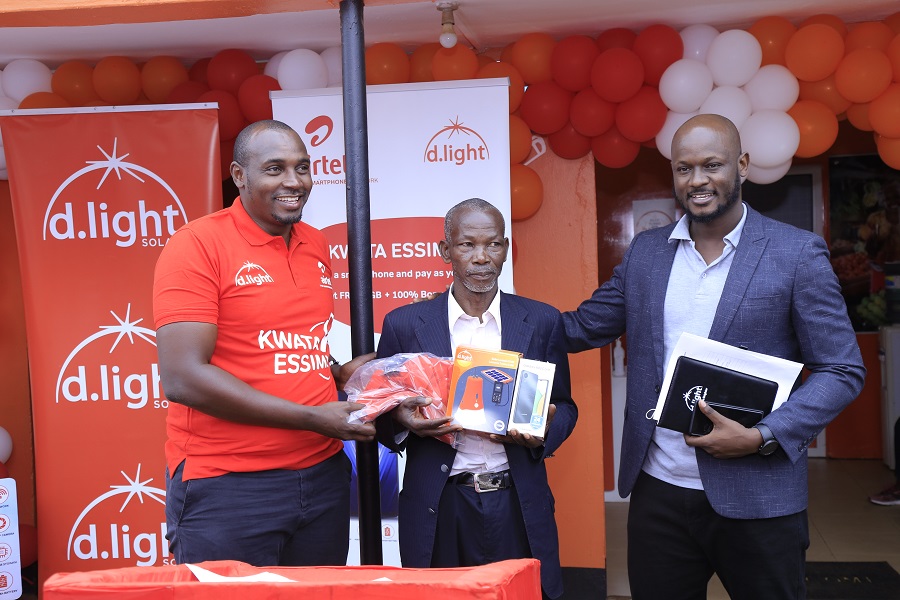 Henry Njoroge (L), Head of Marketing at Airtel Uganda, Douglas Gavala (R), Managing Director at d.light Uganda Limited handing over a gift hamper to Maganda John (C) the first buyer of the smartphone.This was today at the partnership launch between Airtel Uganda and d.light Uganda at Mukono d.light shop.