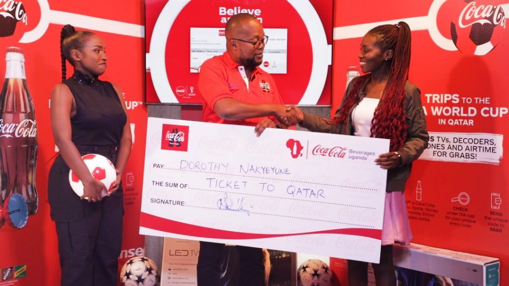 Meet Dorothy Nakyeyune, the 23year Old who Won A Ticket to Qatar for the World Cup under the ‘Coca-Cola Believe and Win’ campaign. Newton Lee Ogong Chanels & Trade Marketing Manager Coca-Cola Beverages Uganda handing over the dummy ticket to the first Ticket winner Dorothy Nakyeyune